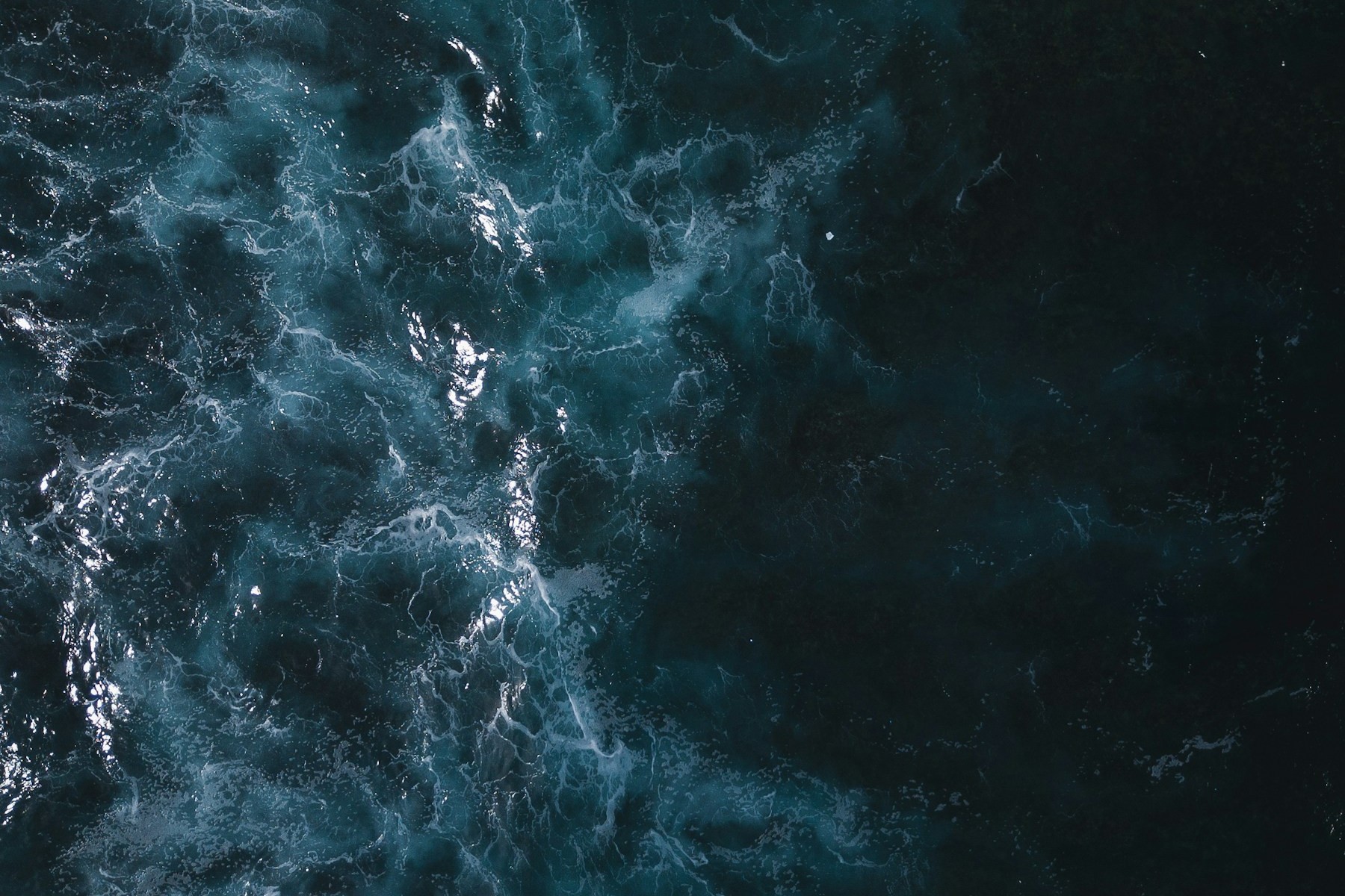 Aerial photograph of white surf flowing through deep blue ocean